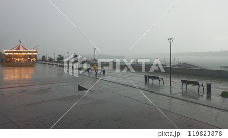 Lonely Deserted Carousel In The Rain With Bright Lights And A Glimmering Reflection On The Ground 119823878