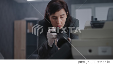 Female criminalist takes photos of evidence at crime scene with camera 119934616