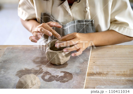 Kids making a craft of a porcelain mug from wet clay 110411034