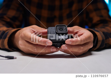 Man holding action camera in hand. It is a compact, lightweight personal camera 110976657