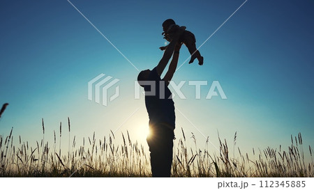 father throws play baby in the park. father's day silhouette happy family child dream concept. father plays with baby throws up. dad play his son in nature in the lifestyle park silhouette at sunset 112345885