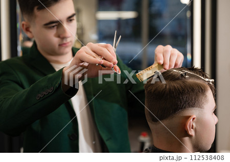 Haircut alignment of the contour of the head with scissors. Short haircut in the barbershop. 112538408