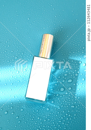 Perfume bottle with mock up on blue background with hard light and water drops. with shadows flat lay, top view 112643481