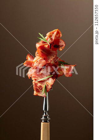 Roasted bacon with rosemary on a fork. 112657550