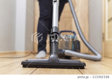 Person vacuuming floor. Household chore and cleaning concept. 113302198