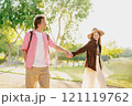 A Young Couple Joyfully Walking Hand in Hand Through a Beautiful Sunlit Park Together 121119762