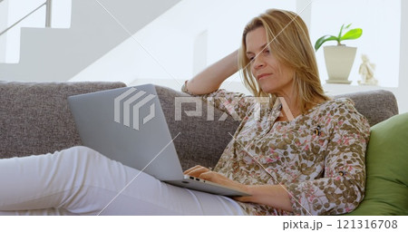 Woman using laptop in living room at home 4k 121316708