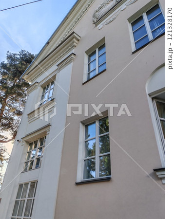 A detailed view of a classical building with clean lines, symmetrical windows, and subtle decorative elements. It emphasizes the timeless beauty of heritage design. 121328170