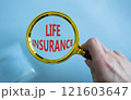 Life insurance symbol. Magnifying glass with words Life insurance. Businessman hand. Beautiful blue background. Business and Life insurance concept. Copy space. 121603647