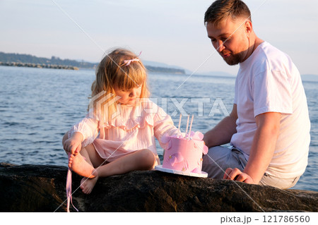 Birthday, parents and children with food by beach for event, celebration and party outdoors. Family, social gathering and mother, father with kids at picnic with cake, presents and eating together 121786560