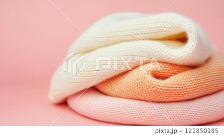 Soft knitted scarves in pastel colors arranged on a pink background. 121850185