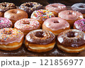 Donuts are a group of different colors and flavors, lying in a row, sprinkled with powdered sugar and caramel. 121856977