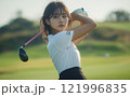 Young woman preparing for a golf swing on a sunny day at a green golf course 121996835