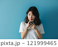 疑問を抱く若い女性：スマホを持ち、思案にふける 121999465