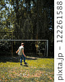 Young man playing soccer near a goal, enjoying a sunny day outdoors. 122261588