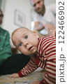 An adorable and curious baby is crawling around with the family in a cozy living room setting 122466902