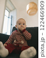 A Cute Baby Dressed in Soft Striped Pajamas Sitting Comfortably Indoors with Joy 122466909