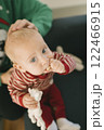 An Adorable Cute Baby Dressed in Red and White Stripes Holding a Colorful Toy in Hand 122466915