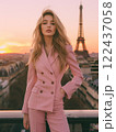 A woman in a pink suit stands on a balcony overlooking the Eiffel Tower 122437058