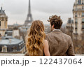 A couple is standing on a balcony overlooking the city of Paris 122437064