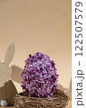 Creative Easter egg shape made of lilac spring petals flowers. Eco-friendly wooden bunnies decoration. Minimal holiday concept still life. Copy space greeting card 122507579