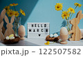 Phrase HELLO MARCH traditional greeting to christian holiday. Festive mood composition with bunnies and yellow flowers on pastel blue background. Sustainable natural materials 122507582