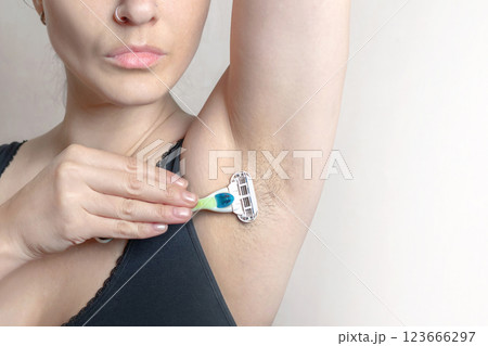 Woman shaves hairy armpits with razor cropped close up copy space 123666297