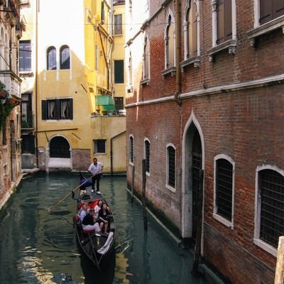 ヴェネツィアの水路をゴンドラで進む観光客（イタリア）の写真