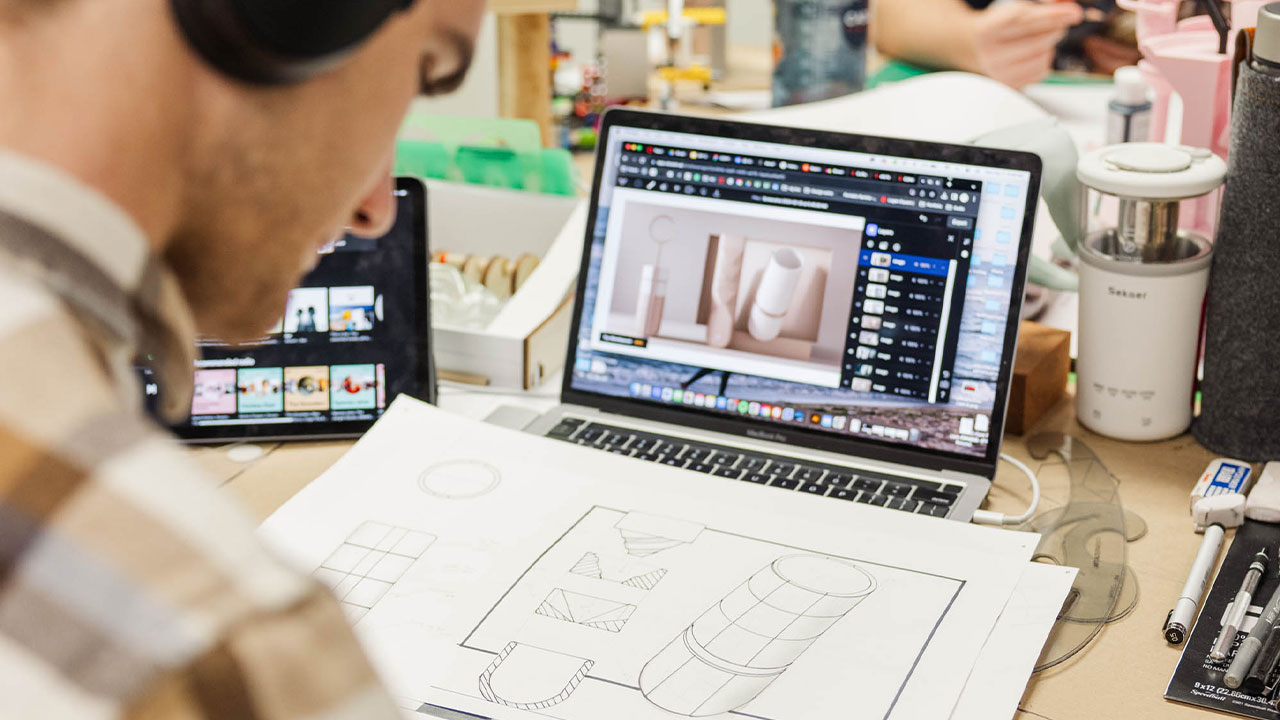 male student working at a computer with architectural drawings