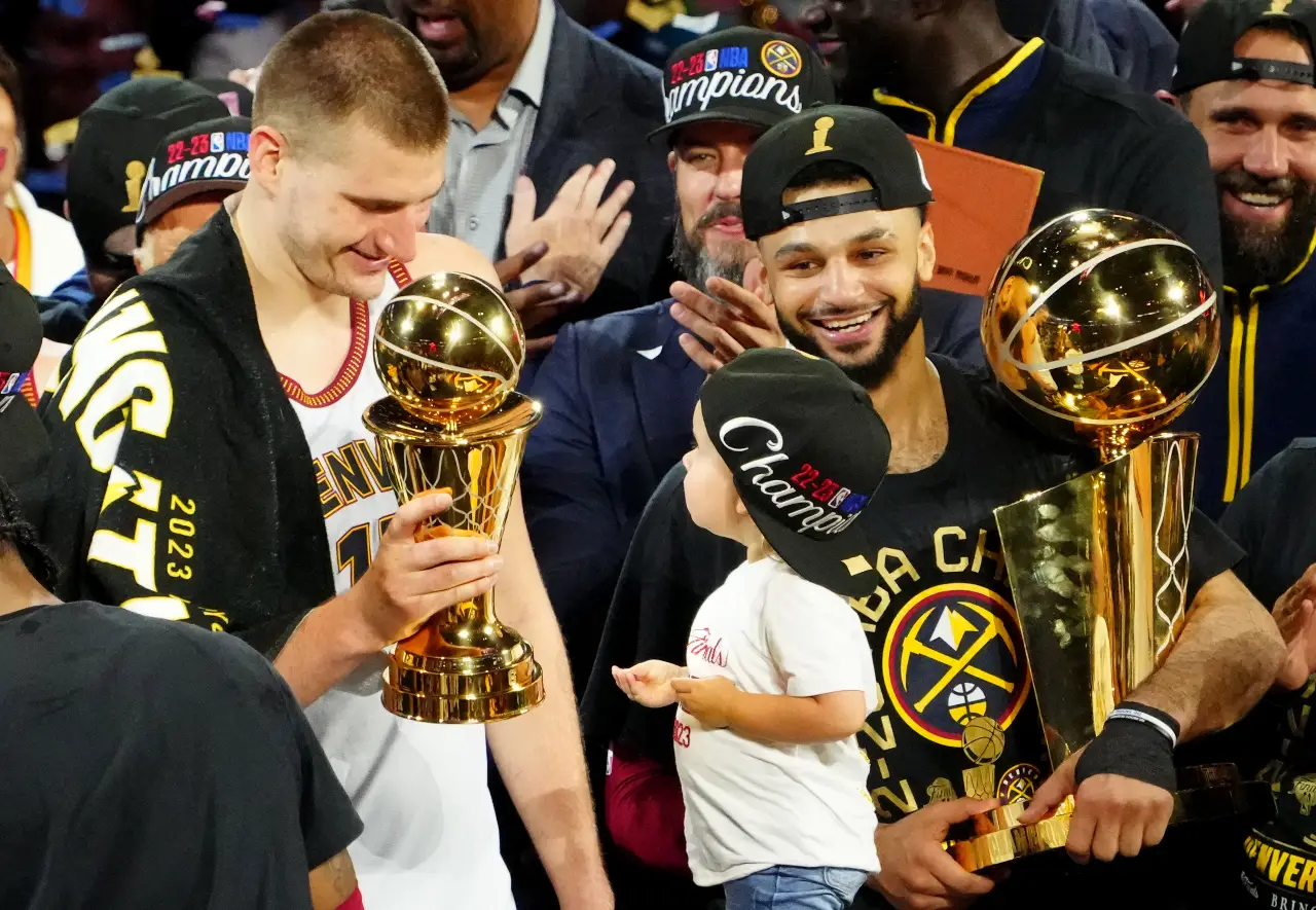 Denver Nuggets center Nikola Jokic (15) celebrates with the Bill Russell NBA Finals MVP Award as guard Jamal Murray (27) holds the Larry O'Brien Trophy after the Nuggets won the 2023 NBA Championship against the Miami Heat at Ball Arena.