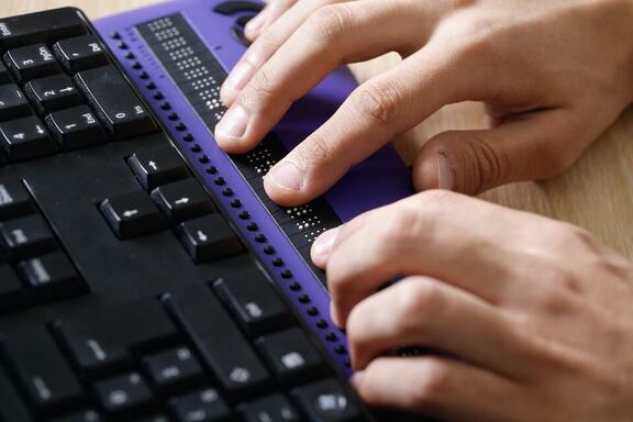 Hands hover over a braille display