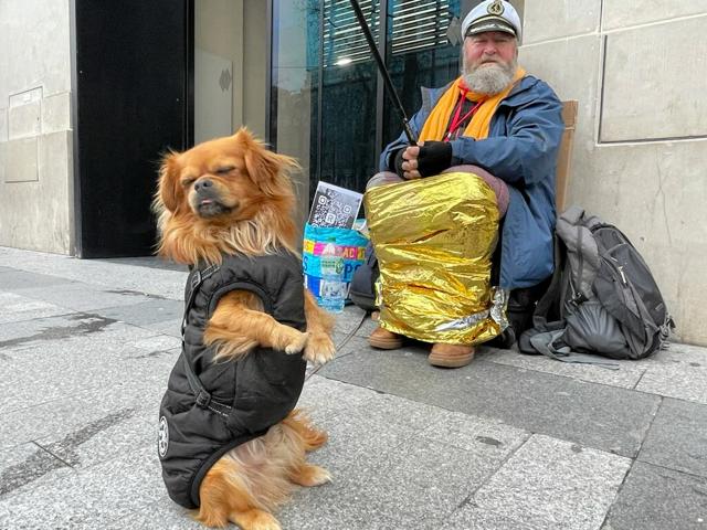 パリのシャンゼリゼ通りに座るマリアンさんと後ろ脚で立つ愛犬のトト=2024年12月10日、宋光祐撮影