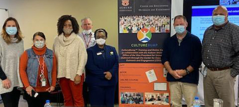 A group of people in masks pose for photo in front of class banner