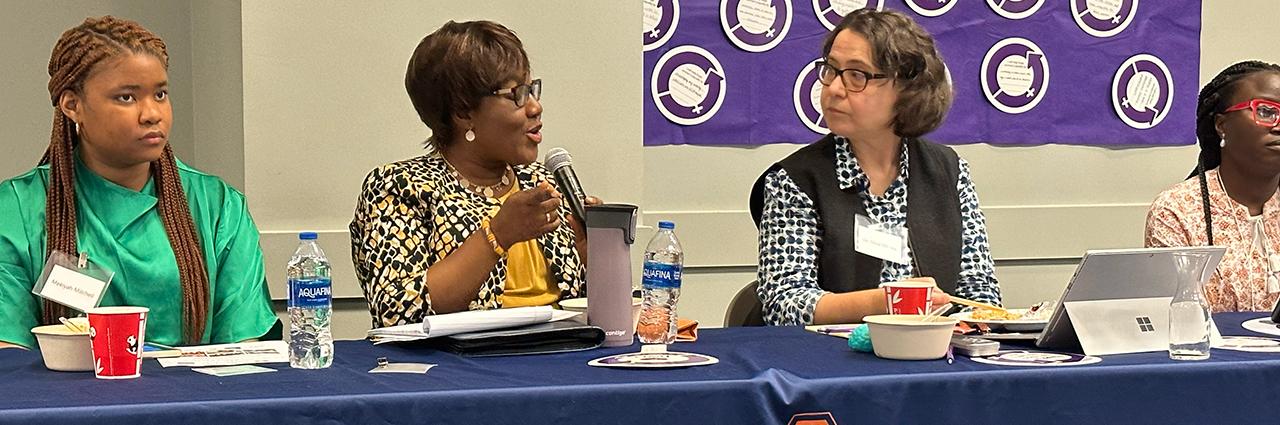 Woman speaking on a panel at an International Women's Day Conference.