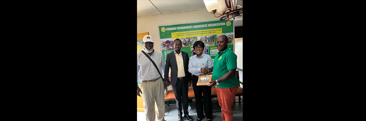 A woman presents a picture frame to a man with two other men standing next to her.