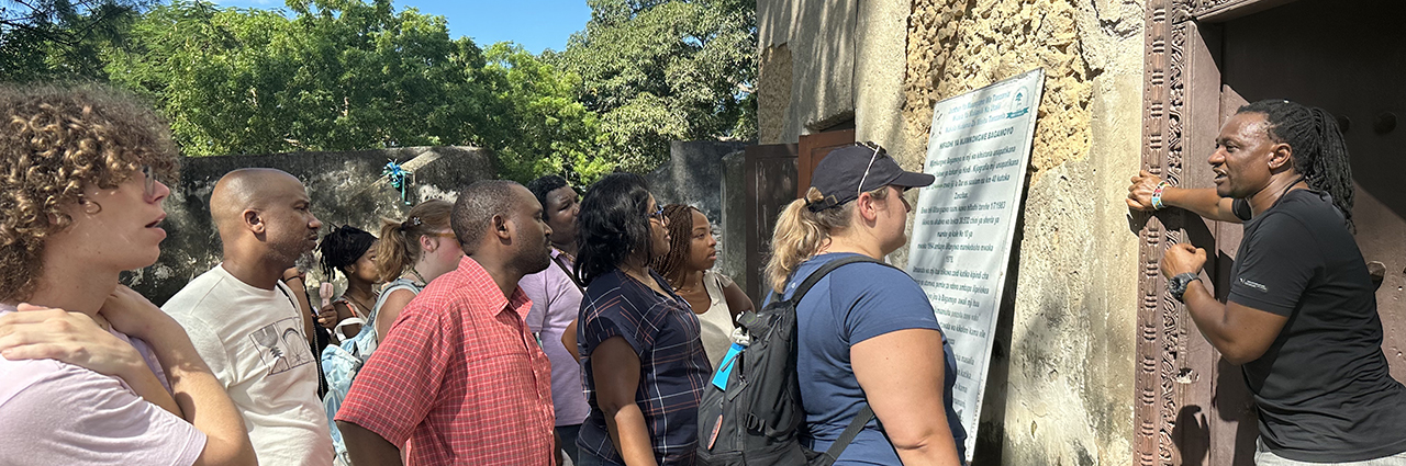 People standing in front a building and listening to a tour guide. 