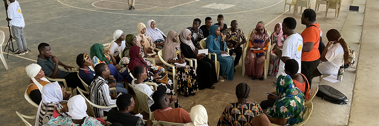 Large group of students sitting and being trained by university students.