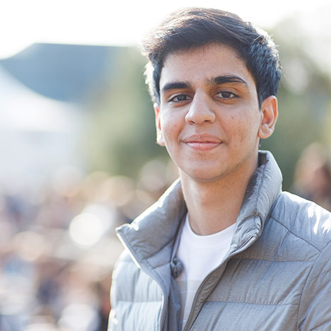 Male student with black hair wearing grey vest