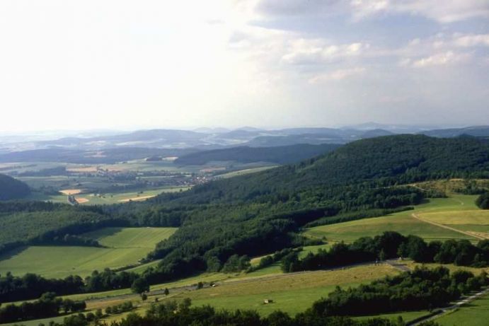 Blick auf eine h&uuml;gelige Wald- und Feldlandschaft