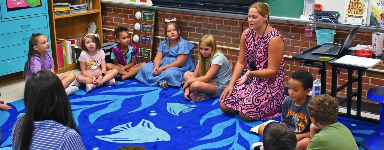 Students sit in a circle in a classroom with their teacher