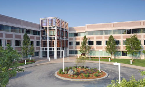 L-shaped brick building with windows with roundabout in front of it