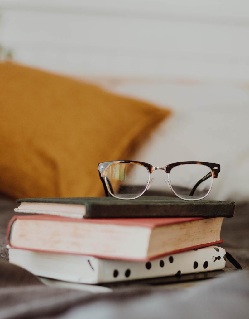 Books with eye glasses on top.