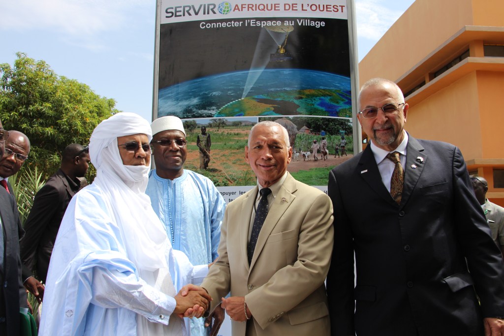 4 men shake hands in front of a SERVIR sign.