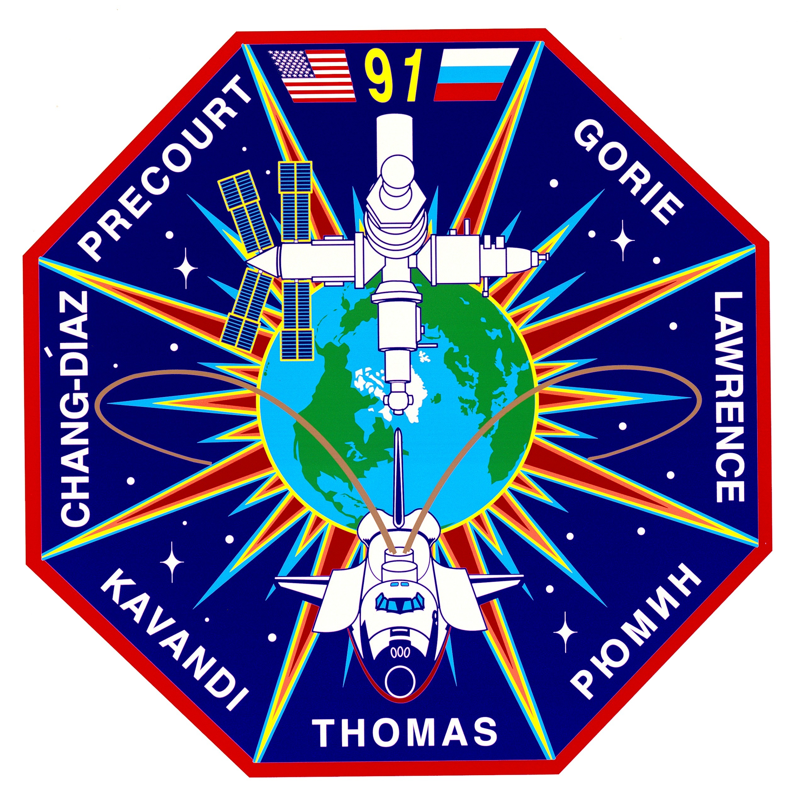 The crew patch for the STS-91 mission depicts the rendezvous of the Space Shuttle Discovery with the Mir space station. The flags of the United States and Russia are displayed at the top of the patch and both countries are visible on Earth behind the two spacecraft. The names of the American crew members surround the insignia on the outer areas.