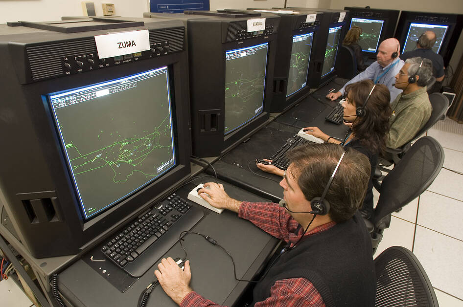 Three people at workstations in ATC simulation lab