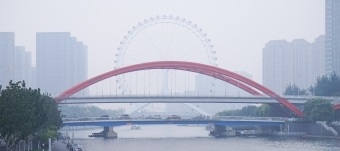 A photograph of Jingang Bridge with the Tianjin Eye behind, shrouded in air pollution.