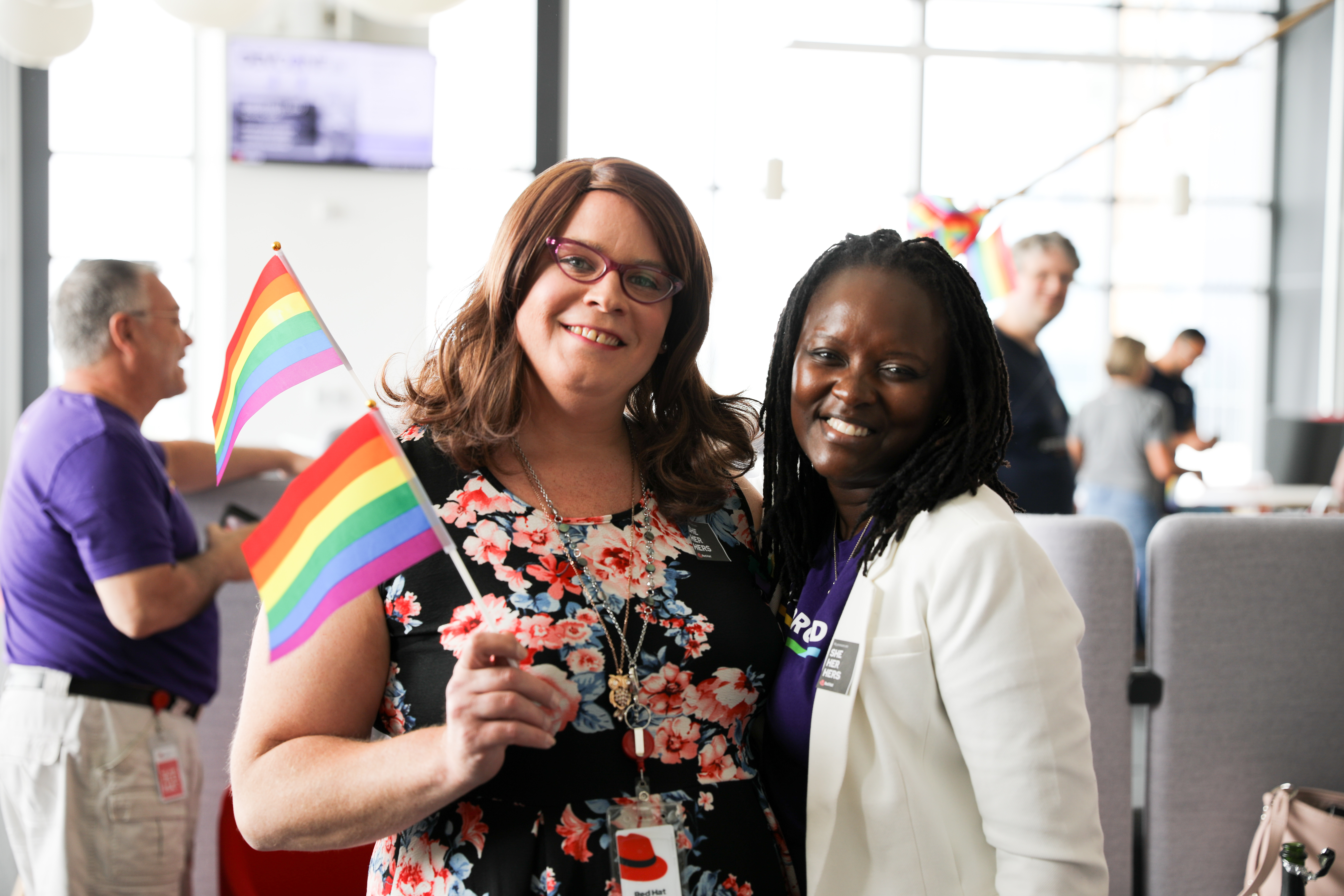 Pessoas funcionárias da Red Hat segurando uma bandeira do orgulho LGBTQIA+