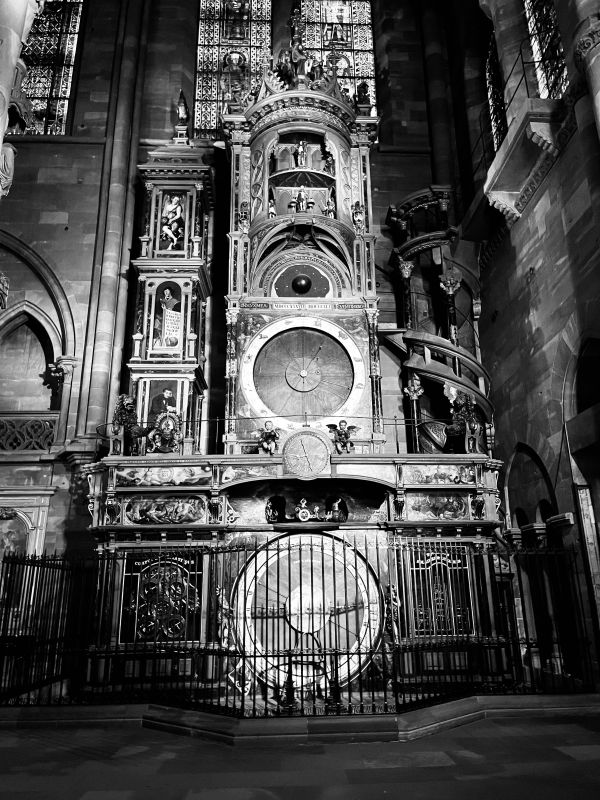 An astronomical clock in a cathedral with vertical layers of circular mechanisms piled up in a tower.