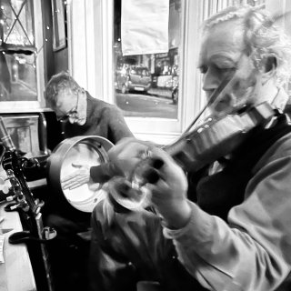 A man playing fiddle with a man playing bodhrán.