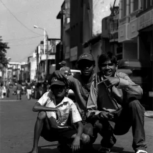 Three boys crouching down in the center of street